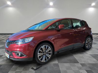 une voiture rouge est garée dans une pièce au sol en damier