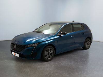 La voiture bleue est garée dans une grande pièce aux murs blancs.
