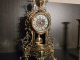 une horloge posée sur une table, à côté de deux bougies