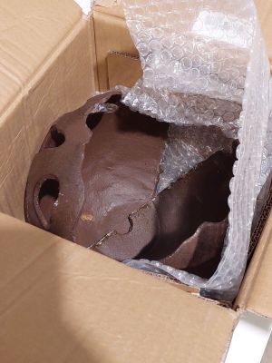 un gâteau au chocolat dans une boîte en carton, enveloppé dans du film alimentaire