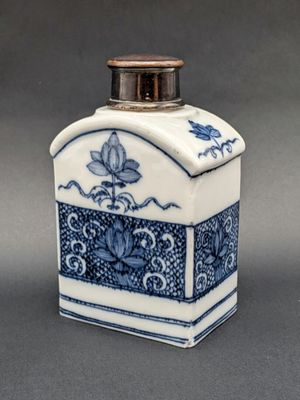 une petite bouteille bleue et blanche ornée d'un motif floral