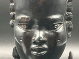 sculpture représentant la tête d'une femme, posée sur un socle posé sur une table