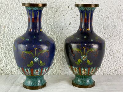 two vases sitting on a table with a white wall in the background