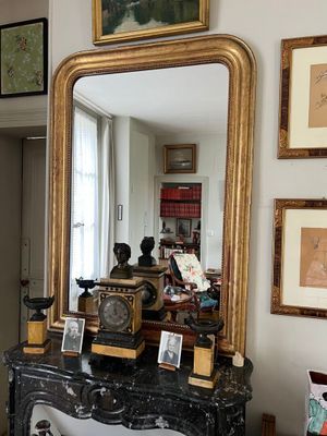 un miroir posé sur une table dans une pièce où sont accrochés des tableaux aux murs