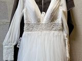 a wedding dress hanging on a hanger next to a brick wall