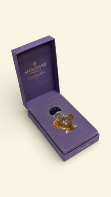 a close up of a purple box with a small bottle of perfume in it