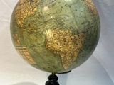a green globe on a black stand on a white background
