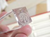 someone is holding a clear piece of glass with a seal on it