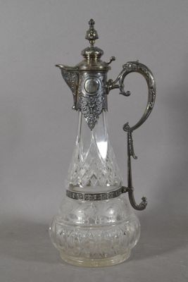 un pichet ancien en verre plaqué argent, muni d'une anse, posé sur une table