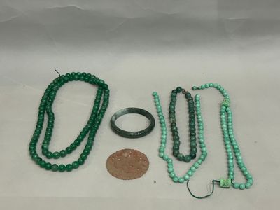 some green beads and a penny are laying on a white surface
