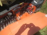 an orange snow plow sitting in the grass