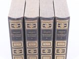four books are lined up in a row on a white surface