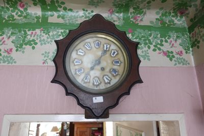 une horloge accrochée au mur au-dessus d'un miroir dans une pièce