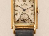 an image of a gold wrist watch with a black leather strap