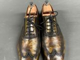 a pair of brown shoes with black laces on a gray surface
