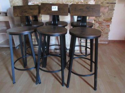 trois tabourets en bois posés sur un parquet, près d'un mur en briques
