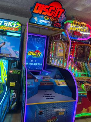 plusieurs bornes d'arcade dans une salle éclairée par des néons