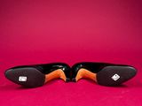 pair of black and orange shoes on a pink background