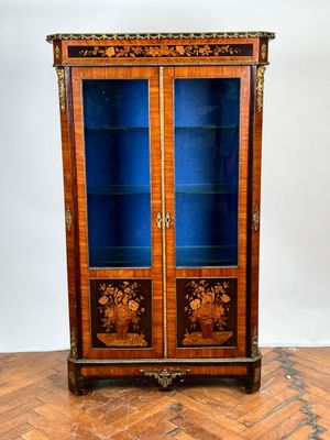 une vieille armoire en bois avec des portes vitrées, posée sur un parquet