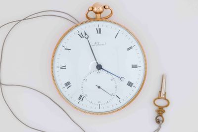 a gold pocket watch and a pair of scissors on a white surface