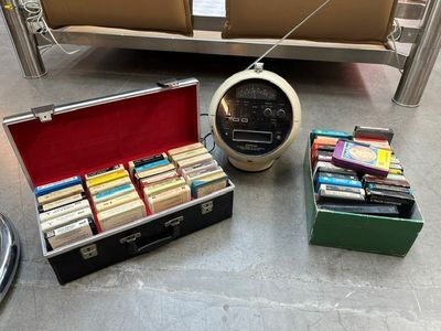many books in a case on the floor next to a couch