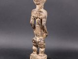 a wooden statue of a woman with a basket on her shoulder