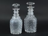 pair of clear glass bottles on a black surface with a black background