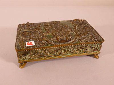 an ornate brass box with a red sticker on top of it