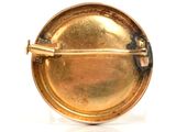 a gold brooch that is sitting on a white surface