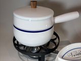 a white saucer with a wooden handle sitting on a stove
