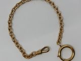 un gros plan d'un bracelet en chaîne dorée sur lequel est enfilé un anneau