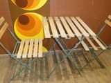 a table and chairs in front of a wall with a painting on it