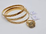three gold rings and a ring on a white surface