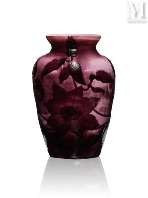 un vase violet orné de fleurs, posé sur une surface blanche