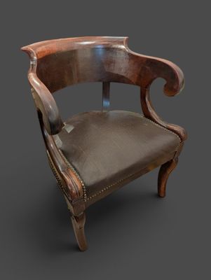 une vieille chaise avec une assise en cuir sur un fond sombre