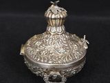 an ornate silver box with a bird on top on a black background