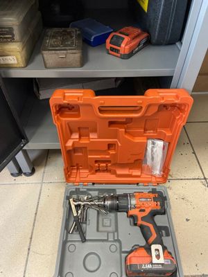 une boîte à outils orange posée sur un sol carrelé, à côté d'une étagère