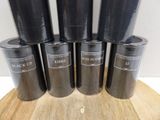 six black ketchup cups sitting on top of a wooden cutting board