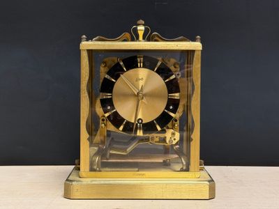 a gold clock sitting on a table with a black background