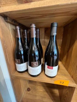 Plusieurs bouteilles de vin sont posées sur une étagère en bois dans un magasin