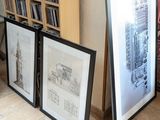 trois photos encadrées posées par terre à côté d'une bibliothèque