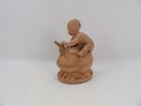 a clay figurine of a boy sitting on a pot