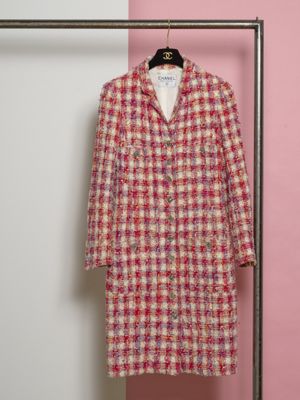 un manteau rose et blanc suspendu à un cintre devant un mur rose