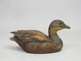 a small bronze duck sitting on a white surface