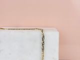 un bloc de marbre blanc sur lequel est posée une chaîne en or