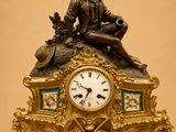 une horloge en bronze sur laquelle est assis un homme