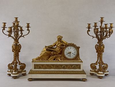 une horloge posée sur une table, à côté de trois chandeliers