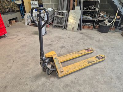 un chariot élévateur rangé dans un garage avec d'autres outils