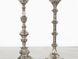 pair of silver candlesticks on a table with a small green object