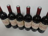 six bottles of wine are lined up on a table